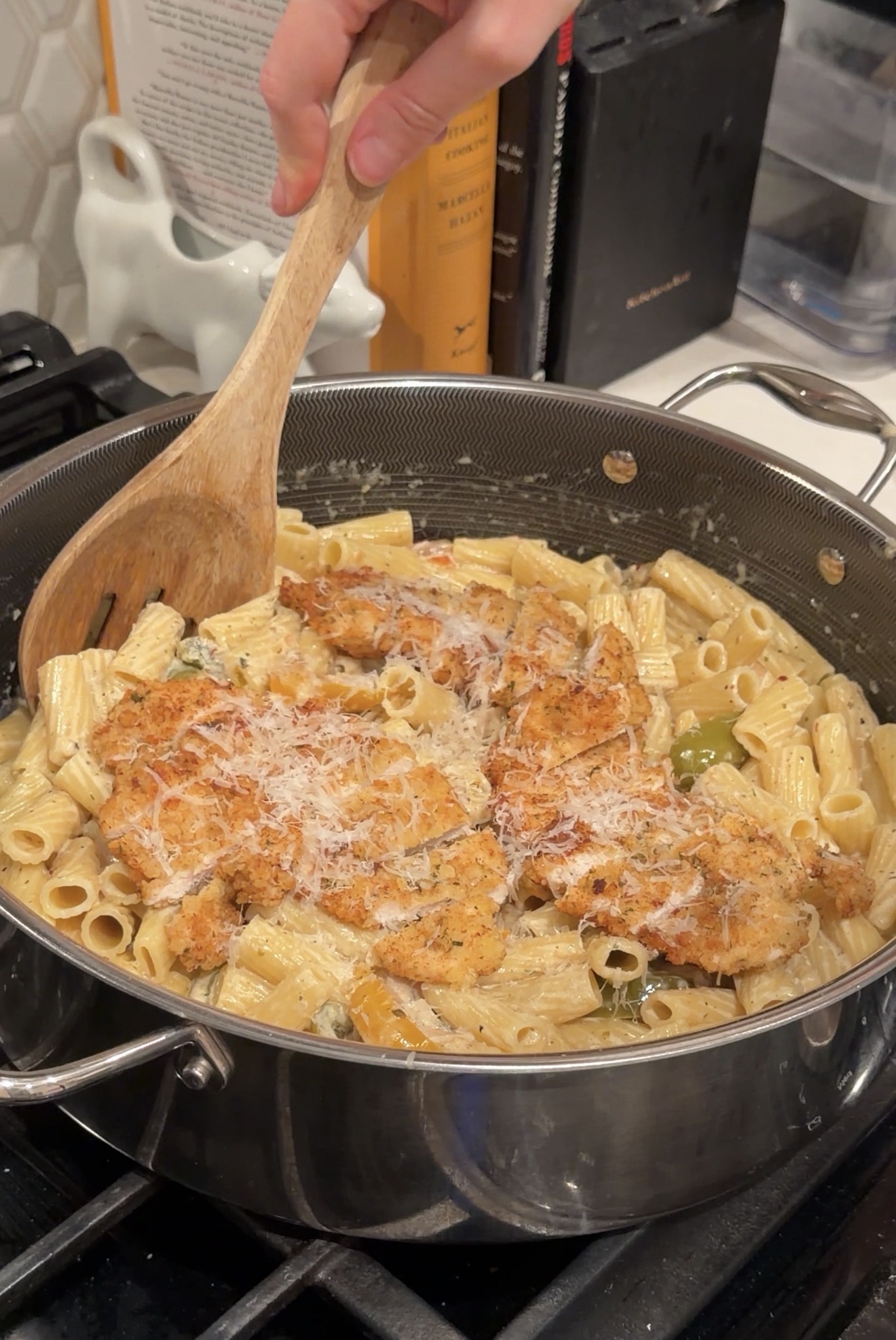 Creamy onion and pepper chicken pasta with rigatoni, topped with crispy chicken and grated Parmesan in a large skillet